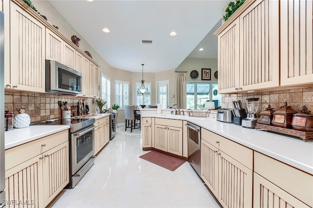 3181 Bramble Cove Ct, Fort Myers, FL 33905 - kitchen featuring appliances with stainless steel finishes, cream cabinets, a peninsula, decorative backsplash, and recessed lighting