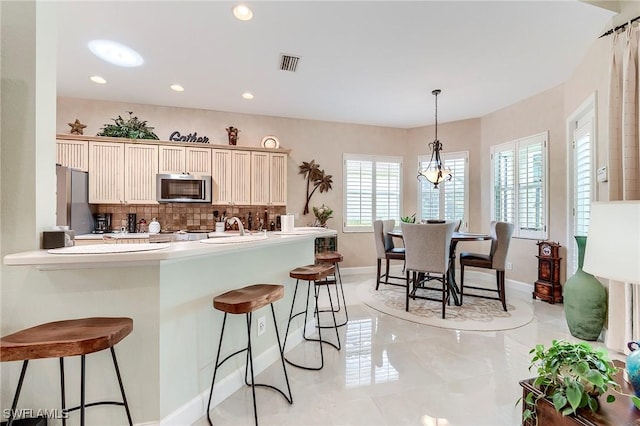 3181 Bramble Cove Ct, Fort Myers, FL 33905 - kitchen featuring appliances with stainless steel finishes, healthy amount of natural light, tasteful backsplash, a kitchen bar, and recessed lighting