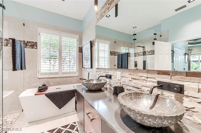 3181 Bramble Cove Ct, Fort Myers, FL 33905 - bathroom with a freestanding bath, a stall shower, double vanity, and tile walls