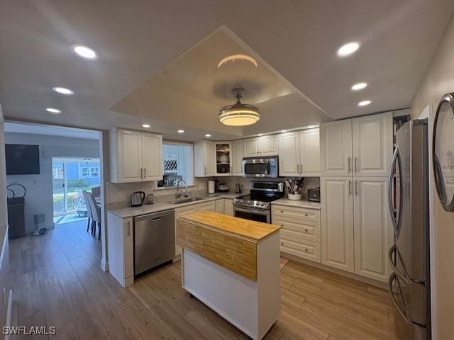 3358 N Key Dr Unit 2, North Fort Myers, FL 33903 - kitchen featuring appliances with stainless steel finishes, a sink, white cabinetry, a tray ceiling, and light wood-style floors