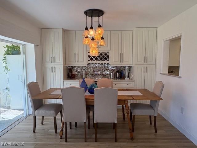 3358 N Key Dr Unit 2, North Fort Myers, FL 33903 - dining space with light wood-style floors, a chandelier, a bar, and baseboards
