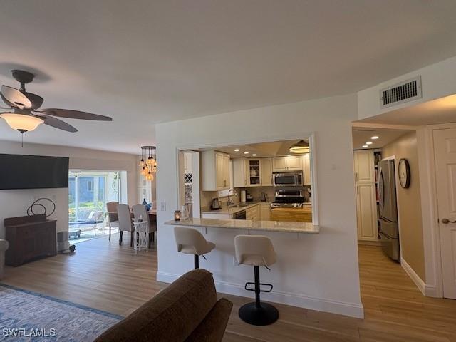 3358 N Key Dr Unit 2, North Fort Myers, FL 33903 - kitchen featuring appliances with stainless steel finishes, light wood-style flooring, light countertops, baseboards, and a kitchen bar