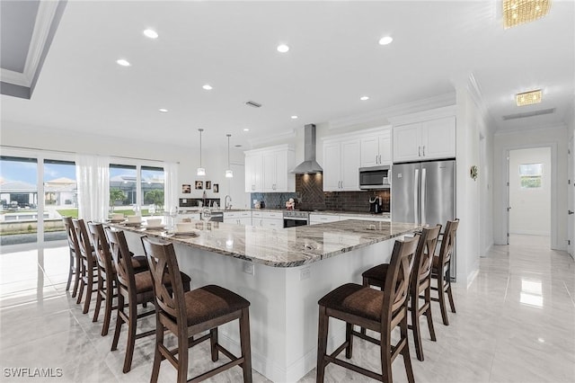 2228 SW 15th Ave, Cape Coral, FL 33991 - kitchen with stainless steel appliances, wall chimney exhaust hood, ornamental molding, backsplash, and white cabinetry