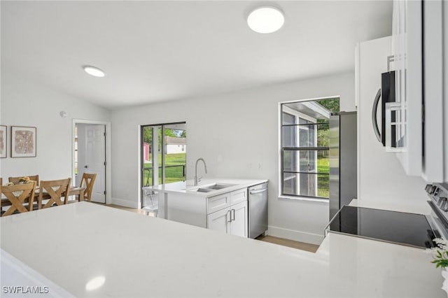 4906 5th St W, Lehigh Acres, FL 33971 - kitchen with stainless steel appliances, a sink, baseboards, white cabinets, and lofted ceiling