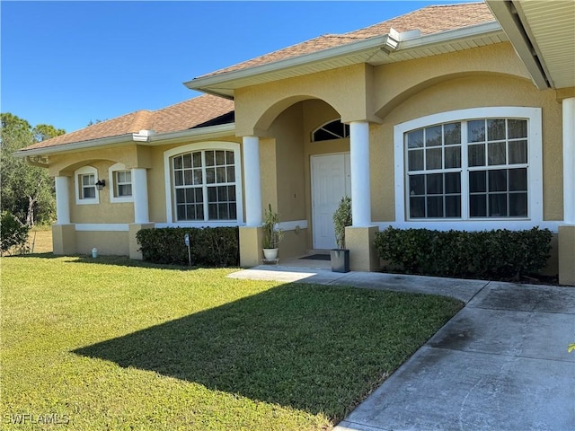 1108 Lee Ave, Lehigh Acres, FL 33972 - property entrance with stucco siding, a lawn, and roof with shingles