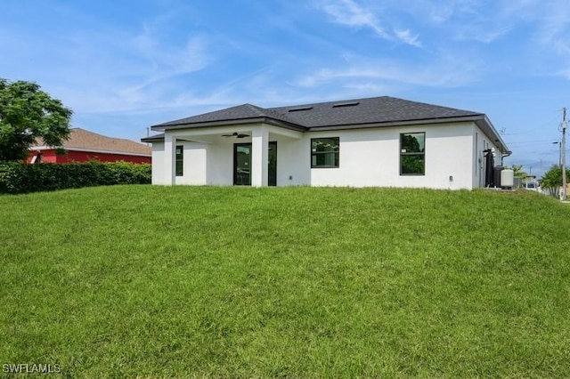 1603 Karen Ave S, Lehigh Acres, FL 33976 - rear view of house with a yard, stucco siding, ceiling fan, and roof with shingles