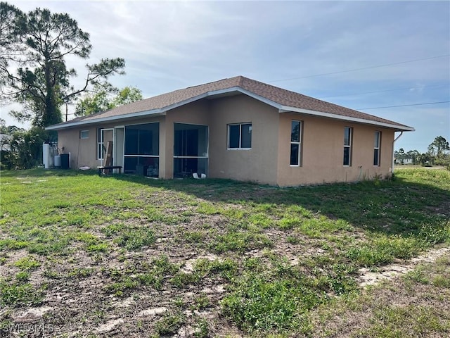 3513 30th St SW, Lehigh Acres, FL 33976 - back of property with stucco siding, a sunroom, and a lawn