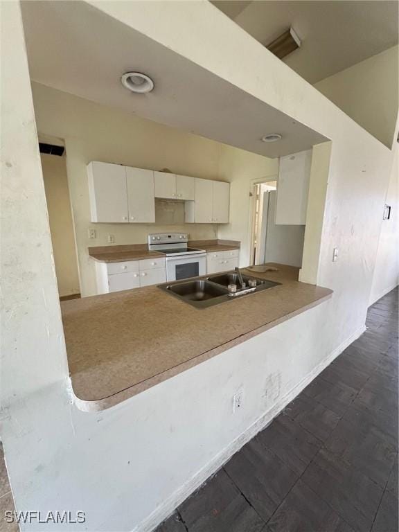 3513 30th St SW, Lehigh Acres, FL 33976 - kitchen with white electric range, a sink, white cabinets, a peninsula, and baseboards