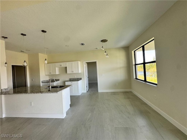 3007 53rd St W, Lehigh Acres, FL 33971 - kitchen with a sink, dark stone counters, white cabinets, baseboards, and a textured ceiling