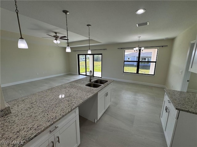 3007 53rd St W, Lehigh Acres, FL 33971 - kitchen featuring a sink, a ceiling fan, white cabinetry, decorative light fixtures, and light stone counters