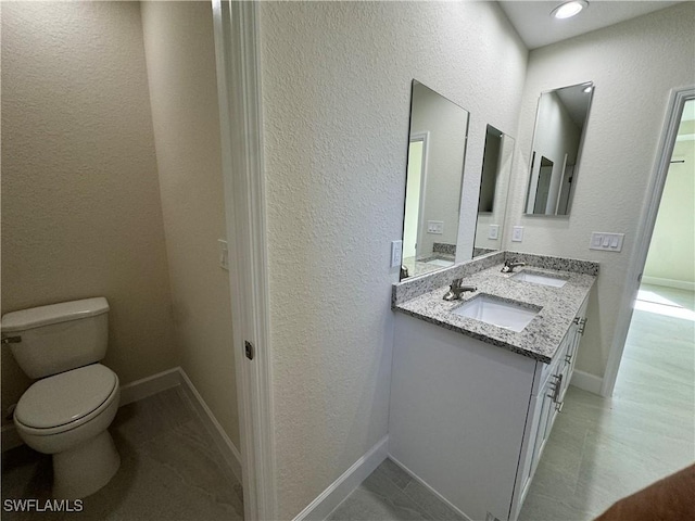 3007 53rd St W, Lehigh Acres, FL 33971 - bathroom featuring toilet, double vanity, a textured wall, and baseboards
