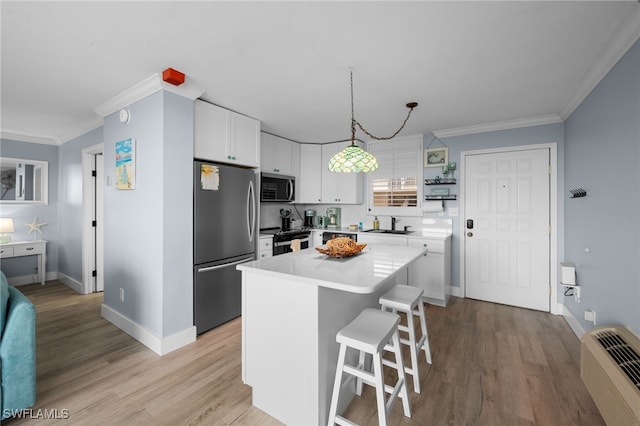 5500 Bonita Beach Rd Unit 502, Bonita Springs, FL 34134 - kitchen featuring appliances with stainless steel finishes, a kitchen bar, white cabinetry, ornamental molding, and baseboards
