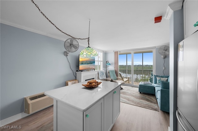 5500 Bonita Beach Rd Unit 502, Bonita Springs, FL 34134 - kitchen featuring stainless steel fridge, a wall unit AC, a kitchen island, light wood-style flooring, and ornamental molding