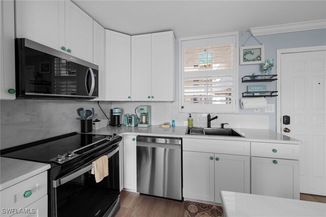 5500 Bonita Beach Rd Unit 502, Bonita Springs, FL 34134 - kitchen featuring appliances with stainless steel finishes, a sink, light countertops, white cabinetry, and crown molding