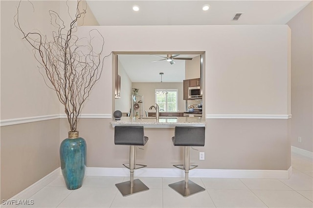 15041 Bridgeway Ln Unit 1006, Fort Myers, FL 33919 - kitchen featuring appliances with stainless steel finishes, ceiling fan, a breakfast bar, a peninsula, and a sink