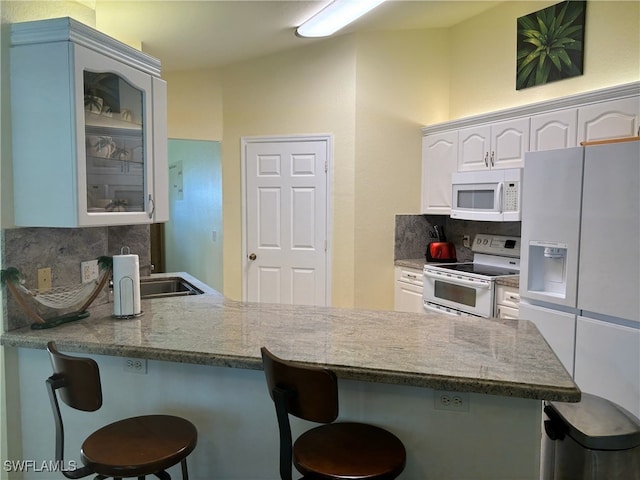 672 Seagrape Dr, Marco Island, FL 34145 - kitchen featuring white appliances, decorative backsplash, glass insert cabinets, and a breakfast bar area