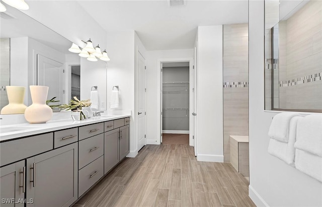7393 Blue Salvia Dr, North Fort Myers, FL 33917 - bathroom featuring double vanity, wood finished floors, a spacious closet, and baseboards
