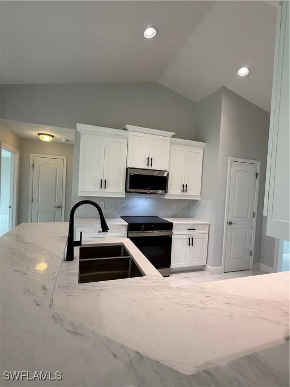 5109 Balmer St, Lehigh Acres, FL 33971 - kitchen featuring stainless steel microwave, black electric range oven, a sink, light stone countertops, and vaulted ceiling