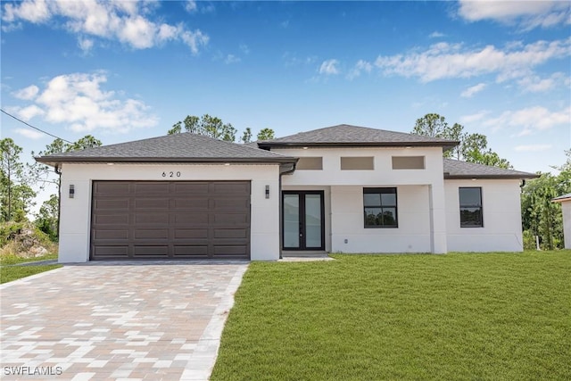prairie-style home with french doors, stucco siding, a front yard, driveway, and a garage