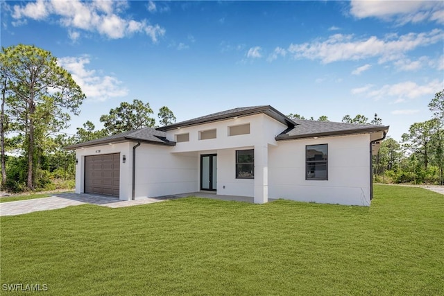 prairie-style house featuring an attached garage, concrete driveway, stucco siding, a front yard, and a shingled roof