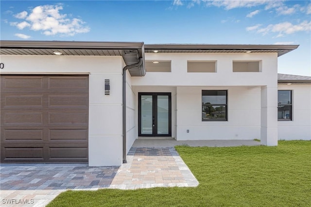 view of front facade featuring french doors, stucco siding, a front lawn, and a garage