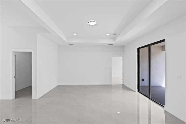 spare room with a raised ceiling, recessed lighting, baseboards, and light marble finish flooring
