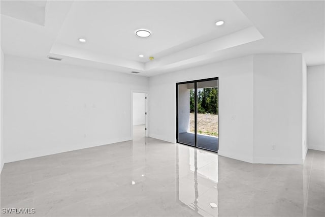 empty room featuring a tray ceiling, light marble finish floors, and recessed lighting