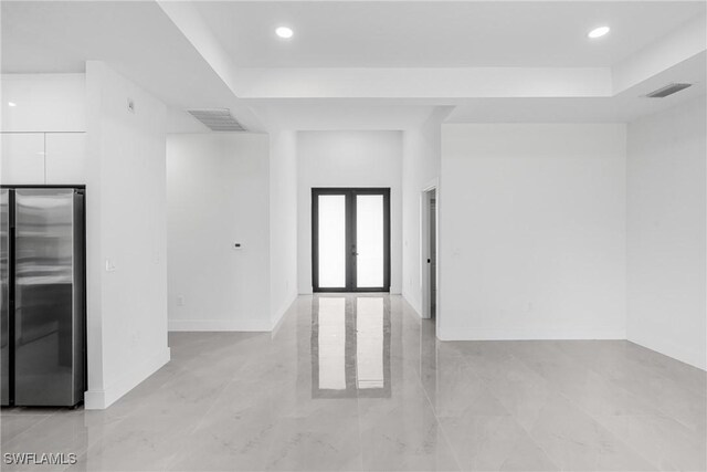 unfurnished room with french doors, recessed lighting, a raised ceiling, and baseboards