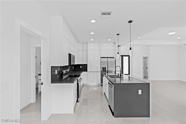 kitchen featuring appliances with stainless steel finishes, modern cabinets, dark countertops, white cabinets, and a sink