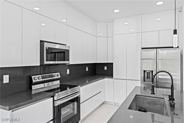 kitchen with appliances with stainless steel finishes, a sink, modern cabinets, white cabinetry, and recessed lighting
