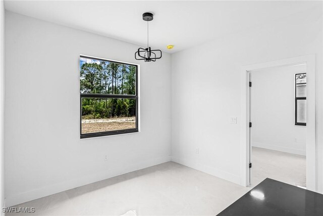 empty room with a chandelier and baseboards