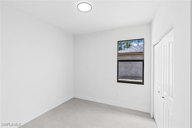 empty room featuring baseboards and light marble finish flooring
