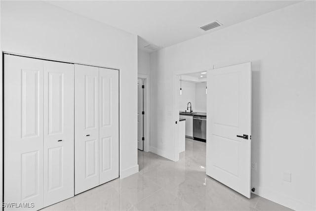 unfurnished bedroom with baseboards, light marble finish floors, a sink, and a closet