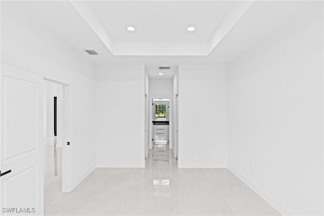 empty room featuring baseboards, recessed lighting, and a raised ceiling