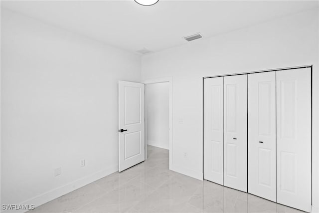 unfurnished bedroom with light marble finish flooring, baseboards, and a closet