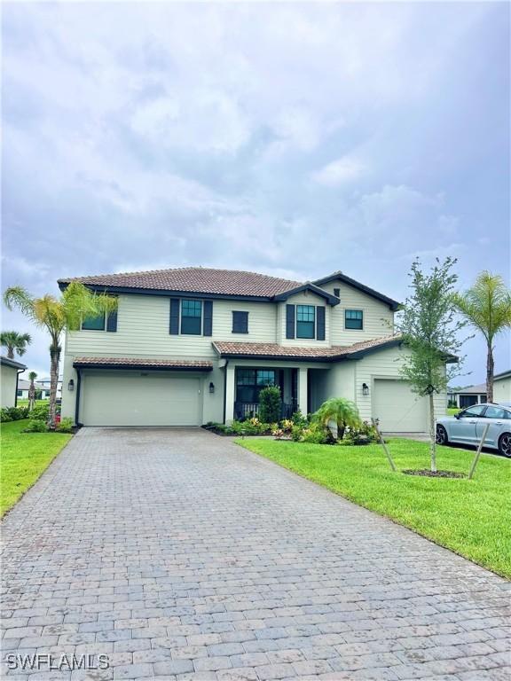 20669 Greenwich Pl, Estero, FL 33928 - traditional-style house featuring decorative driveway, a tiled roof, a garage, and a front yard