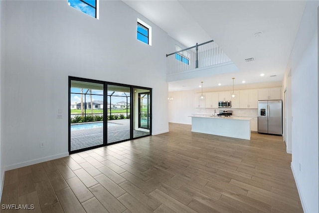 20669 Greenwich Pl, Estero, FL 33928 - unfurnished living room with light wood finished floors, a towering ceiling, and healthy amount of natural light