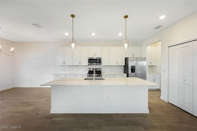 20669 Greenwich Pl, Estero, FL 33928 - kitchen featuring stainless steel appliances, decorative backsplash, white cabinets, a kitchen island with sink, and recessed lighting