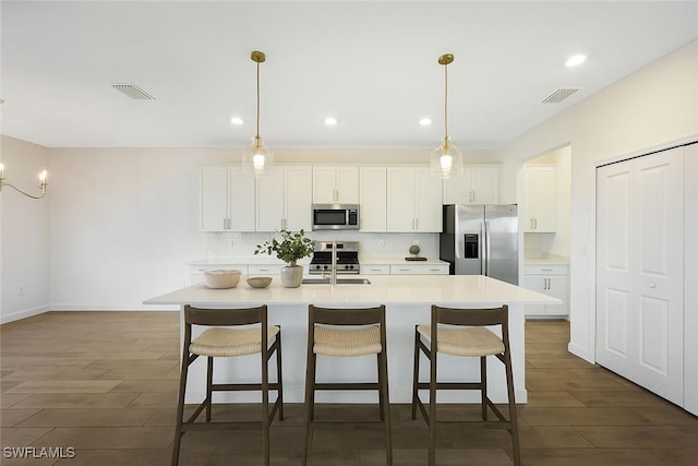 20669 Greenwich Pl, Estero, FL 33928 - kitchen with appliances with stainless steel finishes, dark wood-type flooring, a center island with sink, a kitchen bar, and recessed lighting