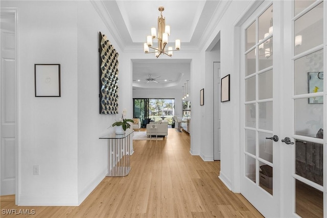 3813 Columbia Ct, Naples, FL 34119 - hallway featuring a tray ceiling, a chandelier, light wood-style floors, baseboards, and ornamental molding