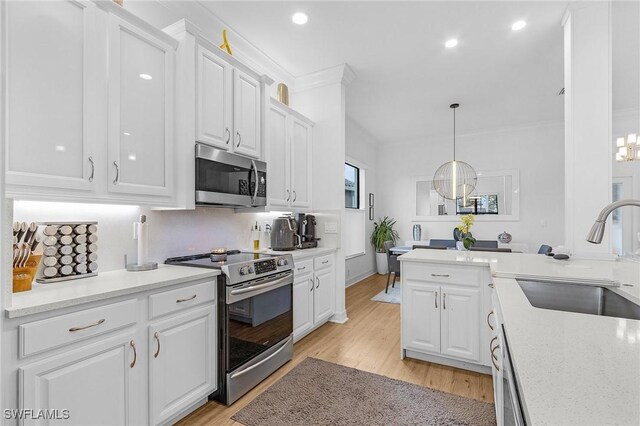 3813 Columbia Ct, Naples, FL 34119 - kitchen with stainless steel appliances, a sink, white cabinetry, light wood finished floors, and crown molding