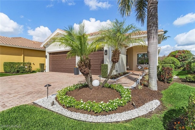 3813 Columbia Ct, Naples, FL 34119 - mediterranean / spanish-style home featuring decorative driveway, an attached garage, stucco siding, and a tile roof
