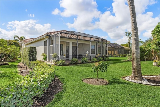 3813 Columbia Ct, Naples, FL 34119 - back of house featuring a yard, stucco siding, glass enclosure, and a tile roof