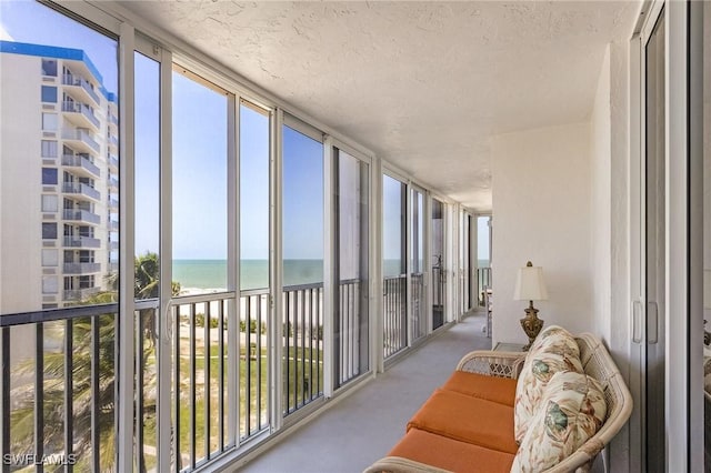 7150 Estero Blvd Unit 706, Fort Myers Beach, FL 33931 - sunroom featuring view of water and beach, expansive windows, plenty of natural light, carpet floors, and a textured ceiling