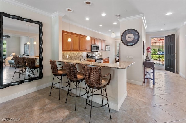 11111 Corsia Trieste Way Unit 101, Bonita Springs, FL 34135 - kitchen featuring appliances with stainless steel finishes, crown molding, light stone counters, light tile patterned flooring, and decorative backsplash