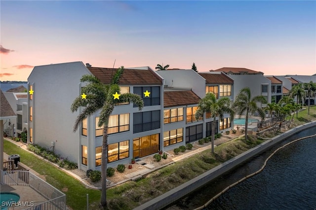 4210 SE 20th Pl Unit A8, Cape Coral, FL 33904 - back of house at dusk featuring a tiled roof, stucco siding, a residential view, and a water view