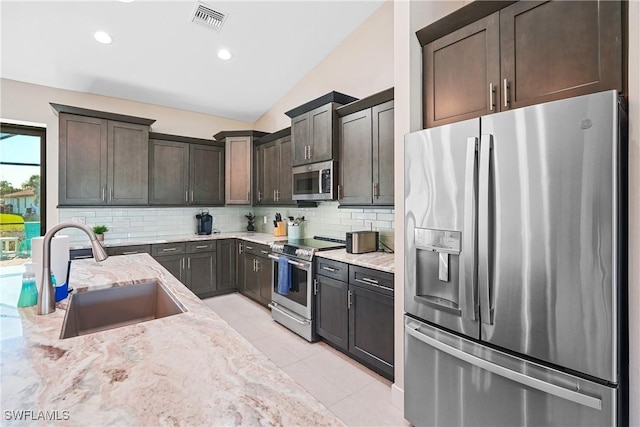 2519 SW 15th Ave, Cape Coral, FL 33914 - kitchen with appliances with stainless steel finishes, a sink, light stone countertops, decorative backsplash, and lofted ceiling