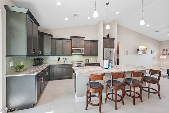 2519 SW 15th Ave, Cape Coral, FL 33914 - kitchen with stainless steel appliances, a kitchen island with sink, decorative backsplash, a kitchen bar, and decorative light fixtures
