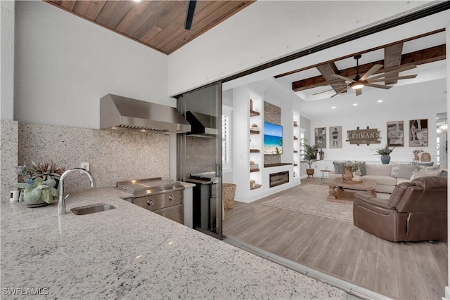20150 Millrun Dr, Estero, FL 33928 - kitchen featuring wall chimney range hood, a sink, light stone countertops, a ceiling fan, and decorative backsplash