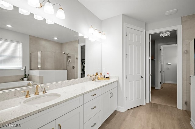 28041 Captiva Shell Loop, Bonita Springs, FL 34135 - bathroom featuring a stall shower, double vanity, a walk in closet, wood finished floors, and a garden tub